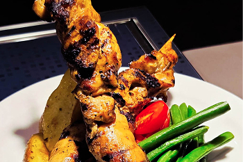 A plate of chicken skewers, potatoes and green beans.