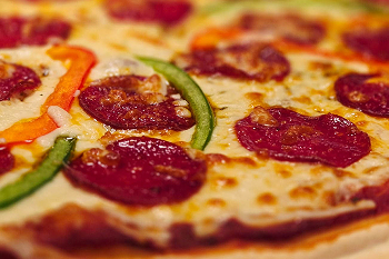 A close up of pizza topped with pepperoni and peppers.